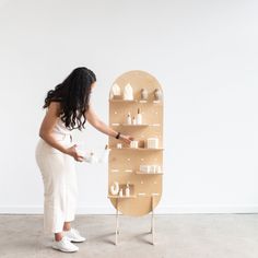 a woman standing next to a wooden shelf