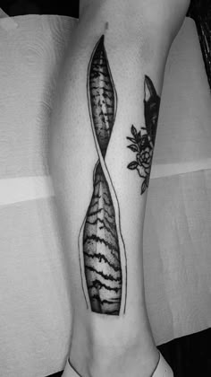 a black and white photo of a woman's leg with an abstract tattoo design on it