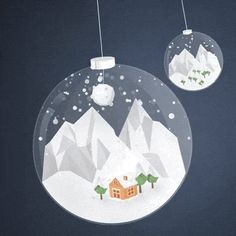 two christmas ornaments hanging from strings in front of snow covered mountains and a small house