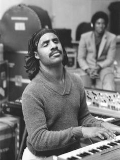 a black and white photo of a man in front of sound equipment with two women behind him