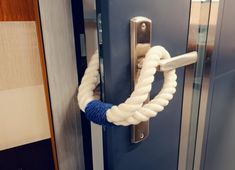 a blue door with a white rope on it and a metal handle that is attached to the door