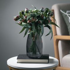 a vase filled with flowers sitting on top of a table next to a book and chair