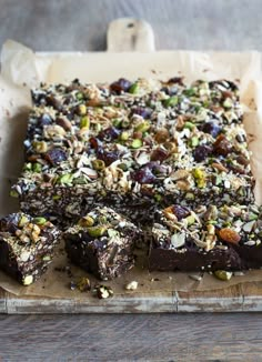 there are many pieces of food on the tray together, including brownies and pistachios