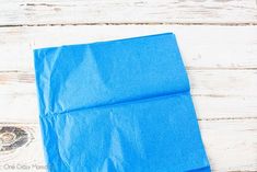 a piece of blue paper sitting on top of a white wooden floor next to scissors