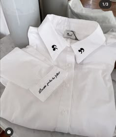 a white shirt with black writing on the chest and collar is sitting on a table