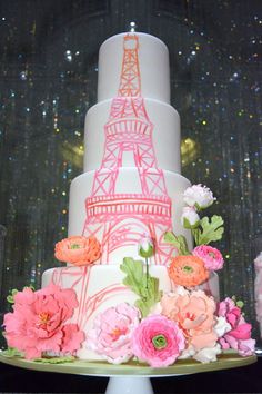 a three tiered cake decorated with flowers and the eiffel tower