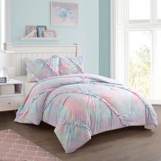 a bed with pink and blue comforters in a room