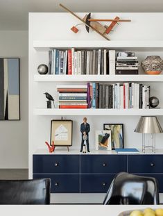 a living room filled with furniture and bookshelves next to a wall mounted clock