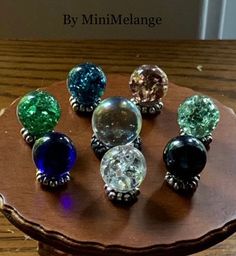 six different colored glass knobs on a wooden table