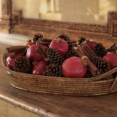 a basket filled with apples and cinnamons on top of a wooden table next to a mirror