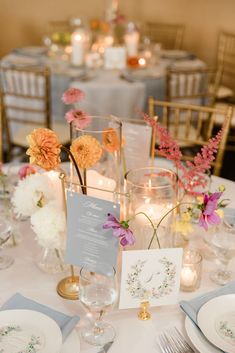 the table is set with wine glasses and flowers