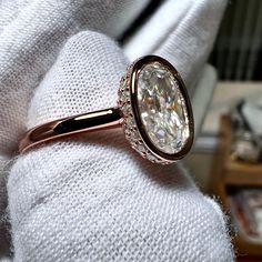 a close up of a person's hand holding a ring with a diamond on it