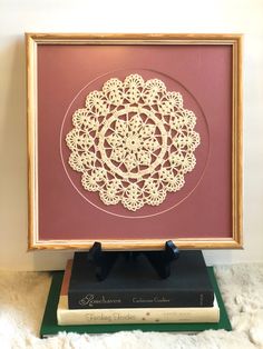 a wooden frame holding a paper doily on top of a book