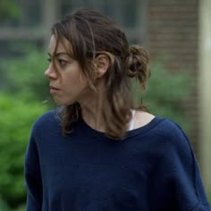 a woman in a blue sweater walking down the street with her hand on her hip