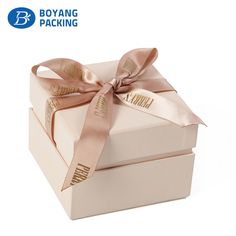 two white boxes with pink ribbons tied around the top and one has a bow on it