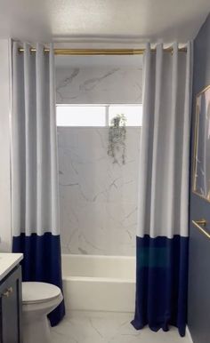 a bathroom with blue and white shower curtain, rug, toilet and sink in it