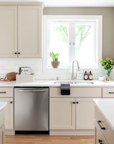 a clean kitchen with white cabinets and stainless steel dishwasher