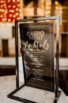 a sign that says casino night cocktails on the side of a table with lights in the background