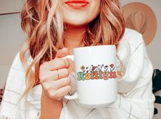 a woman holding a coffee mug with the words happy birthday on it in front of her face