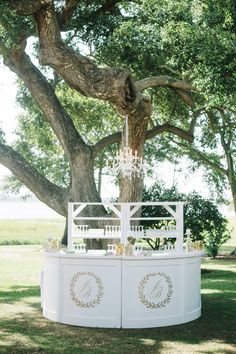 an outdoor ceremony area with a tree and white fence, surrounded by lush green grass