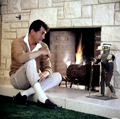 a man sitting on the ground in front of a fire place with his legs crossed