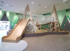 an indoor play area with a slide and climbing wall in the center, surrounded by green walls