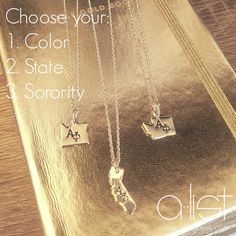 three silver necklaces with letters on them sitting on top of a gold plated surface