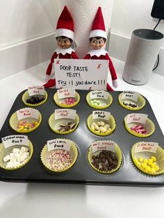 an elf is holding a sign in front of some cupcakes on a tray