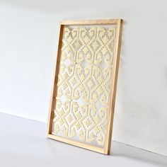 a wooden frame with an intricate design on the front and sides, against a white wall