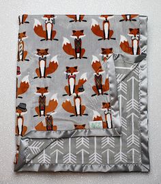 two pieces of fabric with foxes and arrows on them, one is grey and the other is orange