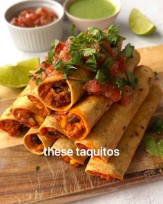 some taquitass are stacked on a cutting board