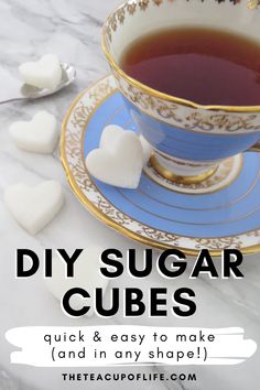 a blue and gold tea cup filled with sugar cubes on top of a marble table