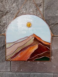 a stained glass mountain scene hanging on a stone wall