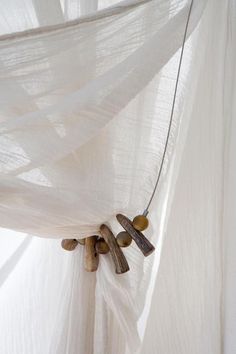 a white curtain with some wooden beads hanging from it's side and on the inside