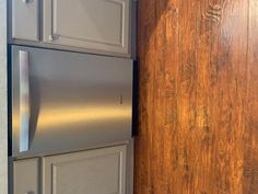 a metallic refrigerator freezer sitting next to a wooden wall