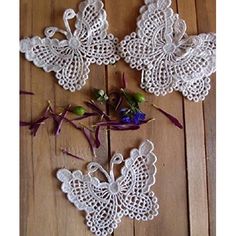 crocheted doily with flowers and butterflies on wooden floor next to each other