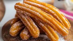 some sugar covered churros on top of a wooden plate with powdered sugar