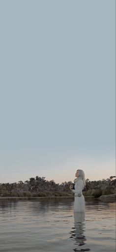 a person standing in the water with their head above her body and looking up into the sky