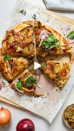 a pizza sitting on top of a wooden cutting board next to onions and other vegetables