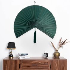 a green fan hanging on the wall above a dresser