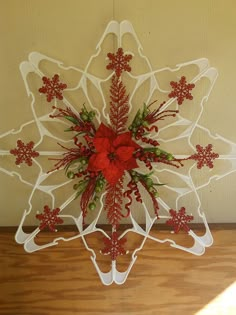 a decorative snowflake with red flowers and greenery on it's side