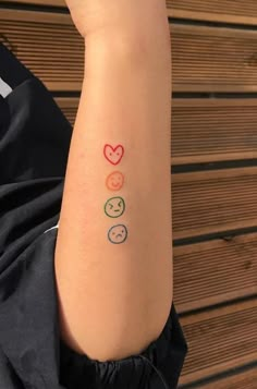 a person with a tattoo on their arm that has three faces and hearts painted on it