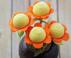 three orange flowers in a brown vase on a wooden table with white sprinkles