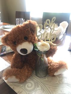 a teddy bear sitting on top of a table next to a vase filled with flowers