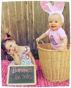 a baby sitting in a basket next to a sign that says bunnies for sale