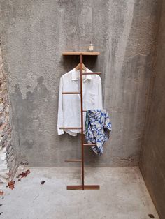 a shirt hanging on a clothes rack next to a wall with a coat hanger