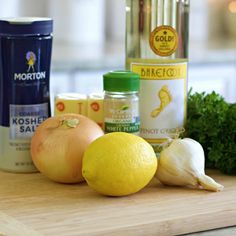 an assortment of ingredients on a cutting board including lemons, garlic and seasoning