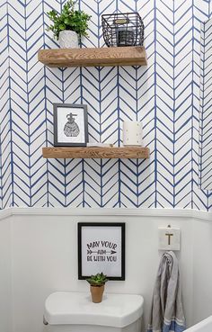 a white toilet sitting next to a bath tub in a bathroom with blue and white wallpaper