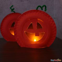 two pumpkin shaped lanterns sitting on top of a table