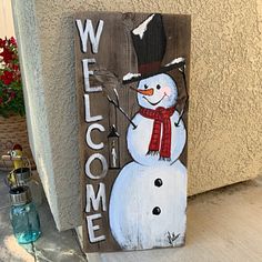 a wooden sign with a snowman painted on it